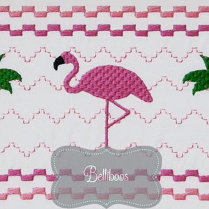 May include: Embroidered design featuring a pink flamingo standing on a gray base with the text "Belliboos" below. Two green palm trees are on either side of the flamingo. The background is white with pink and red zig-zag and checkered patterns.