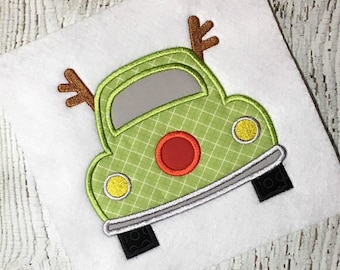 May include: Green car with a red circle and yellow headlights. The car has brown antlers on top.