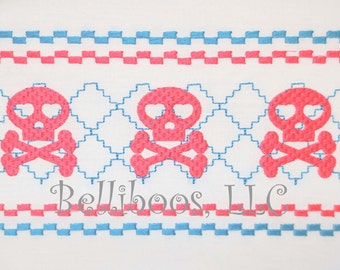 Puede incluir: Tres diseños de calaveras y huesos cruzados de color rosa con corazones por ojos, bordados sobre un fondo de tela blanca con bordes a cuadros azules y rosas. El texto "Belliboos, LLC" está bordado debajo de las calaveras.