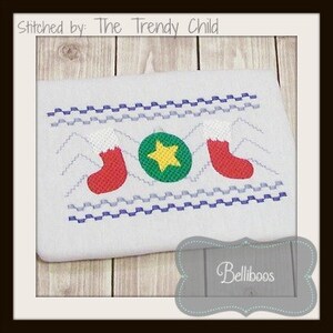 May include: Embroidered design featuring two red stockings with white cuffs, a green circle with a yellow star, and a blue and white zig-zag pattern. The design is stitched on a white fabric.