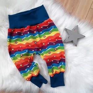 Könnte beinhalten: Regenbogen gestreifte Babyhose mit weißen Sternen und blauen Bündchen.