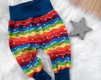 Puede incluir: Pantalones de bebé a rayas arcoíris con estrellas blancas y puños azules.
