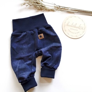 Puede incluir: Pantalones de bebé azules con una estrella en el bolsillo trasero. Los pantalones tienen una cintura y puños elásticos azul marino.