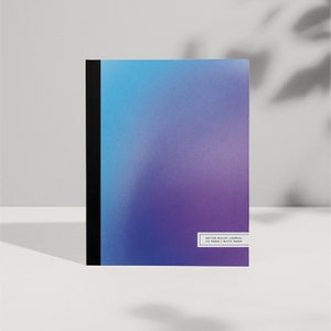 Può includere: Un diario a punti con sfumatura blu e viola e rilegatura nera. La copertina riporta il testo "DOTTED BULLET JOURNAL 100 PAGES | WHITE PAPER".