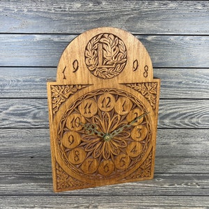 May include: A wooden clock with a carved face and Roman numerals. The clock has a decorative arch with the numbers 1998 on it.
