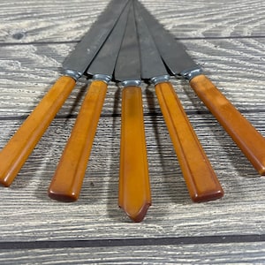 May include: Set of six vintage butter knives with brown plastic handles and silver blades.