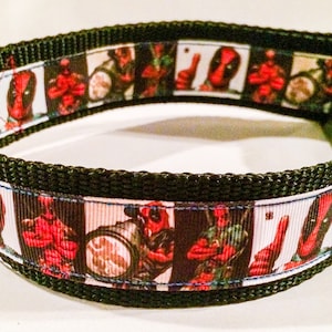Puede incluir: Un collar negro para perros con un patrón repetido de imágenes del cómic de Deadpool en rojo, blanco y negro. El collar tiene una base de nailon negro, una anilla en D de metal y una hebilla de plástico.