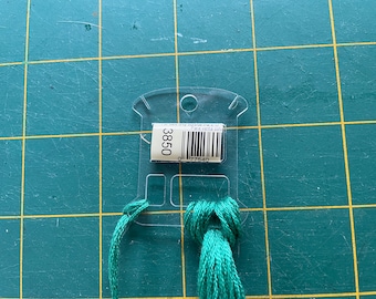 May include: A green embroidery floss wound around a clear plastic floss bobbin with a label that reads "3850".