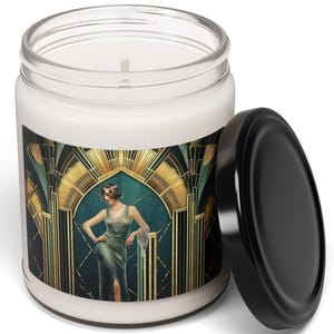 May include: A white candle jar with a black lid. The jar features a vintage art deco design with a woman in a green dress. The design has gold and teal accents. The candle is a decorative home item.