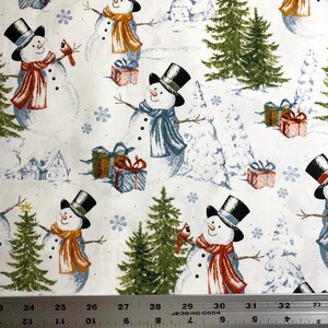 Puede incluir: Tela blanca con un patr&oacute;n repetido de mu&ntilde;ecos de nieve con sombreros de copa y bufandas en tonos naranja, azul y rojo. El dise&ntilde;o incluye pinos verdes, regalos envueltos y copos de nieve. Una regla est&aacute; en la parte inferior.