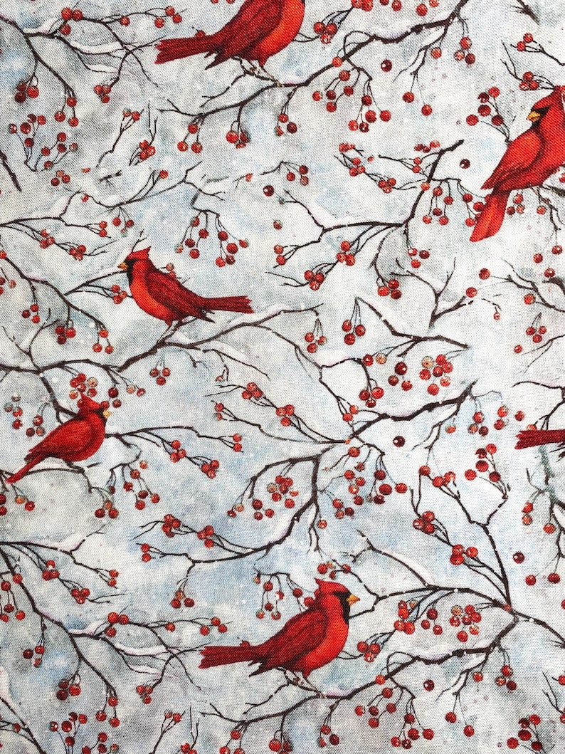 May include: A repeating pattern featuring bright red cardinals perched on branches with red berries against a light blue and white background. The branches are dark brown, creating a contrast with the birds and berries.