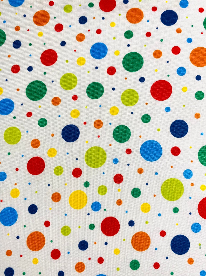 May include: White fabric with a repeating pattern of colorful polka dots in various sizes. The dots are in shades of red, orange, yellow, green, and blue. The fabric has a slightly textured appearance.
