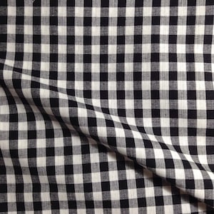 May include: Black and white gingham fabric with a subtle texture. The fabric is folded in half, creating a diagonal line.