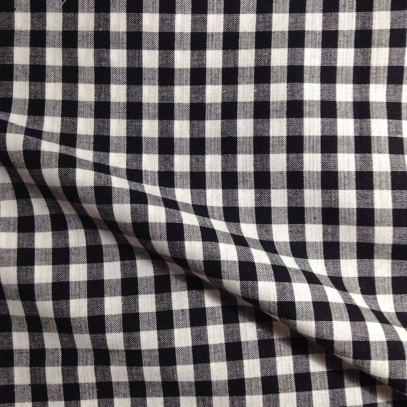 May include: Black and white gingham fabric with a subtle texture. The fabric is folded in half, creating a diagonal line.