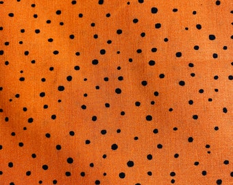 May include: A fabric textile featuring a vibrant orange background covered in a dense, irregular pattern of small, solid black polka dots of varying sizes scattered across the entire surface of the material in a random, non-uniform arrangement.