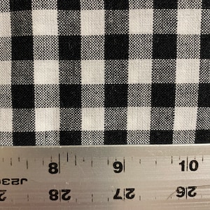 May include: Black and white gingham fabric with a ruler showing 8 inches. The fabric has a small check pattern.