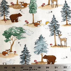May include: White fabric with a repeating pattern of brown bears, foxes, deer, and pine trees. The background is a light beige with brown and green accents. The fabric is measured with a ruler in inches.