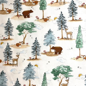 May include: A white fabric with a repeating pattern of brown bears, deer, foxes, and trees. The trees are green and blue with brown trunks. The background is white with brown clouds.