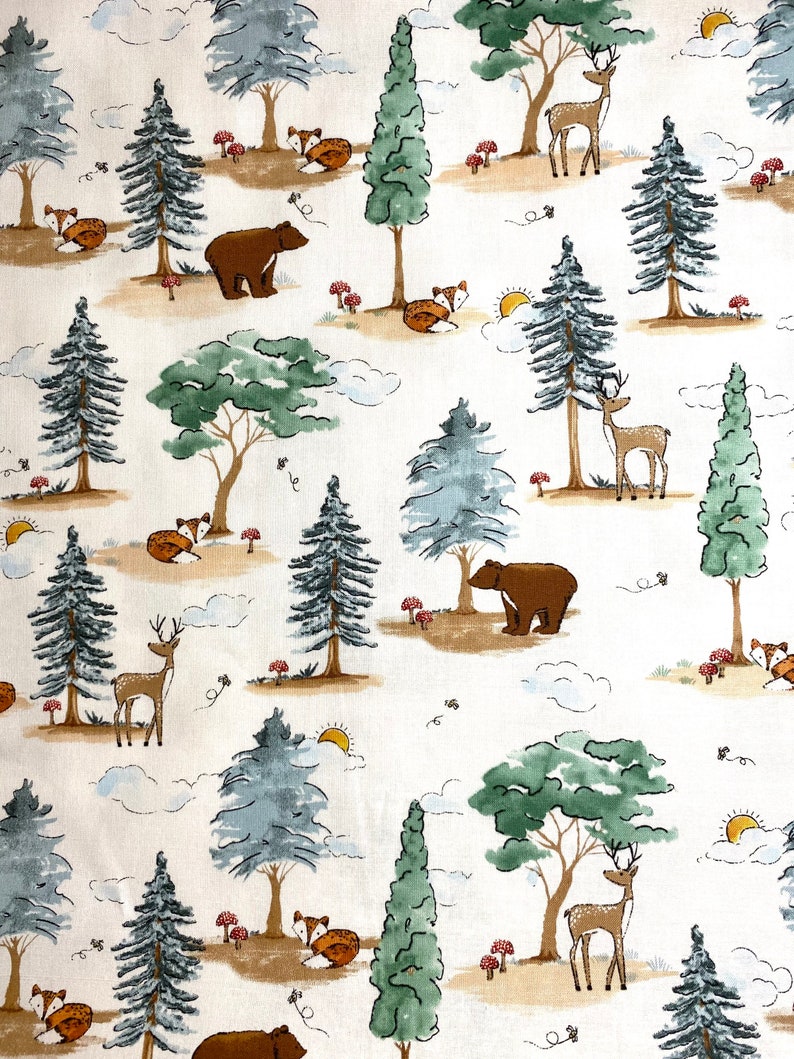 May include: A white fabric with a repeating pattern of brown bears, deer, foxes, and trees. The trees are green and blue with brown trunks. The background is white with brown clouds.