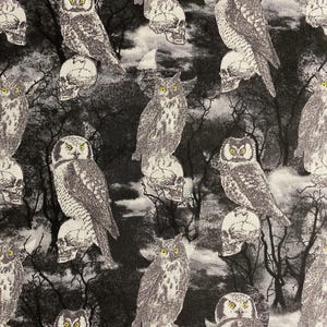 May include: A black and white fabric featuring a repeating pattern of owls perched on skulls. The owls have yellow eyes and are set against a backdrop of bare trees and a cloudy sky. The design has a spooky, Halloween theme.