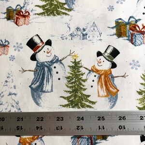 Puede incluir: Tela blanca con un patr&oacute;n repetido de mu&ntilde;ecos de nieve, &aacute;rboles de Navidad, copos de nieve y regalos envueltos. Los mu&ntilde;ecos de nieve llevan sombreros de copa y bufandas. Los regalos tienen envoltorios azules, rojos y dorados. Los &aacute;rboles son verdes.