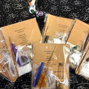 May include: Six brown paper bags containing various spell kits for witchcraft. Each bag includes a candle, herbs, crystals, and other magical ingredients. The bags are labelled with the name of the spell and the ingredients included.
