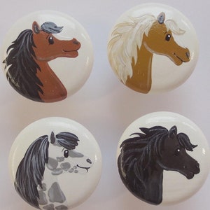 Könnte beinhalten: Vier runde weiße Keramikknöpfe mit bemalten Pferde-Designs. Die Pferde sind nach rechts gerichtet und haben unterschiedliche Farben und Markierungen. Die Knöpfe haben einen Durchmesser von etwa 5 cm.