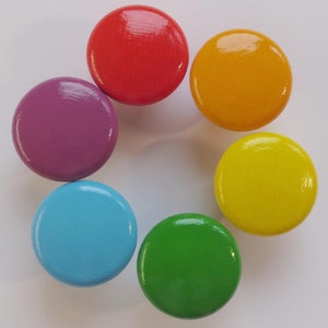 Könnte beinhalten: Sechs runde Holzgriffe in Regenbogenfarben: rot, orange, gelb, grün, blau und lila.