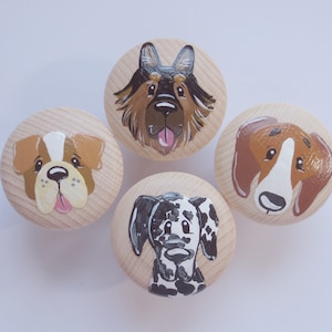 Könnte beinhalten: Vier Holzknöpfe mit bemalten Hundefiguren. Die Hunde sind ein Schäferhund, eine Bulldogge, ein Beagle und ein Dalmatiner.