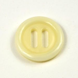 Può includere: Un bottone rotondo giallo pallido con due fori rettangolari. Il bottone ha un bordo leggermente rialzato e arrotondato e una superficie liscia. Questo accessorio per cucito è adatto a vari progetti di abbigliamento.