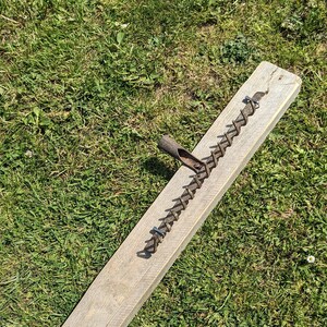 May include: A rustic wooden board with a metal chain attached to it. The chain is made of metal links and has a hook at one end. The board is weathered and has a natural wood finish.