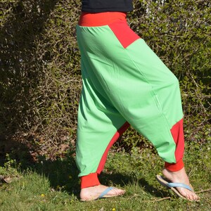 May include: Green and red harem pants with a wide leg and a loose fit. The pants have a red waistband and red trim around the legs.