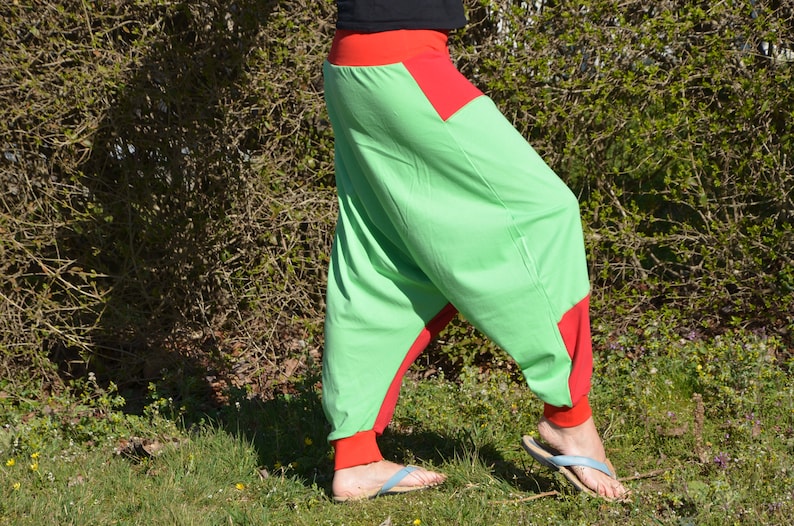 May include: Green and red harem pants with a wide leg and a loose fit. The pants have a red waistband and red trim around the legs.