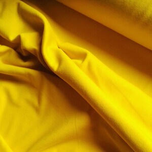 Könnte beinhalten: Nahaufnahme eines leuchtend gelben Stoffes, der die Textur und die Falten des Materials zeigt.