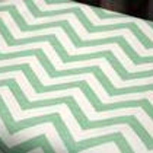 Könnte beinhalten: Nahaufnahme eines Stoffes mit einem sich wiederholenden Zickzackmuster. Das Muster zeigt abwechselnd Streifen in Weiß und Hellgrün. Der Stoff scheint aus Baumwolle oder Leinen zu sein.