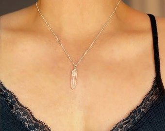 May include: A silver chain necklace with a clear quartz crystal pendant.