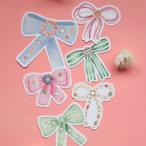 May include: Six watercolor illustrations of bows with various colors and patterns, including blue, green, pink, and white. The bows are decorated with jewels and pearls.