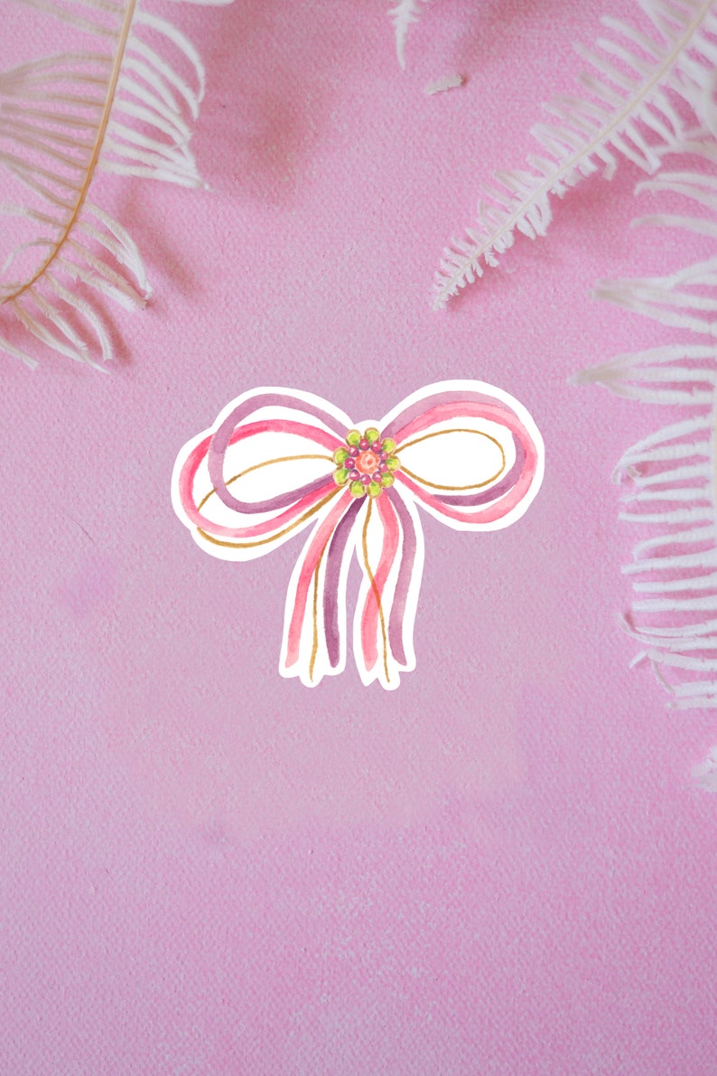 May include: A watercolor illustration of a pink and purple bow with gold accents and a green and pink beaded center.