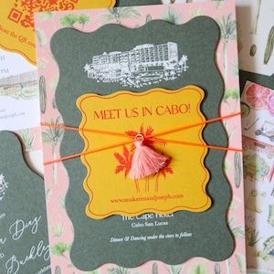 May include: A yellow and orange invitation with a tassel, featuring the text "Meet us in Cabo!" and the website address "www.anakarenandjoseph.com". The invitation also includes the text "The Cape Hotel, Cabo San Lucas" and "Dinner & Dancing under the stars to follow".