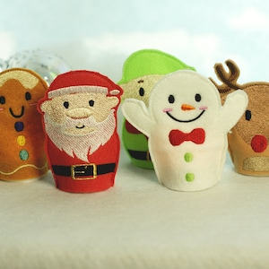 May include: Set of five felt finger puppets featuring a gingerbread man, Santa Claus, an elf, a snowman, and a reindeer. The puppets are all smiling and have embroidered details.