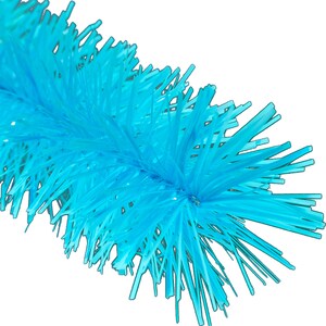May include: A close-up of a bright blue bottle brush with a long, thin handle. The bristles are made of soft, flexible plastic and are designed to clean the inside of bottles.