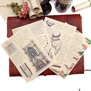May include: A set of vintage-style paper ephemera with handwritten text and illustrations. The papers feature a gothic church, a blindfolded figure, and a floral design. The papers are on a brown leather journal.