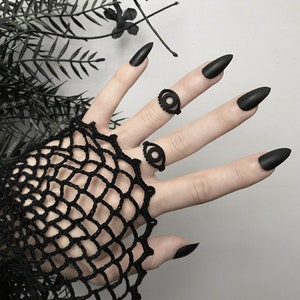 Matte black 3d printed eye ring displayed on a gothic model hand with long black nails