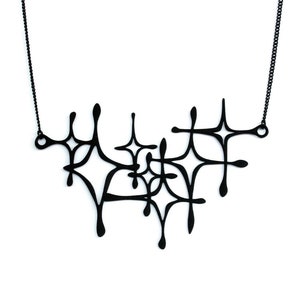 Matte black mid-century modern atomic sparkle necklace displayed on a white background. Witchy 3d printed jewelry by Salem, MA artist Hypnovamp.