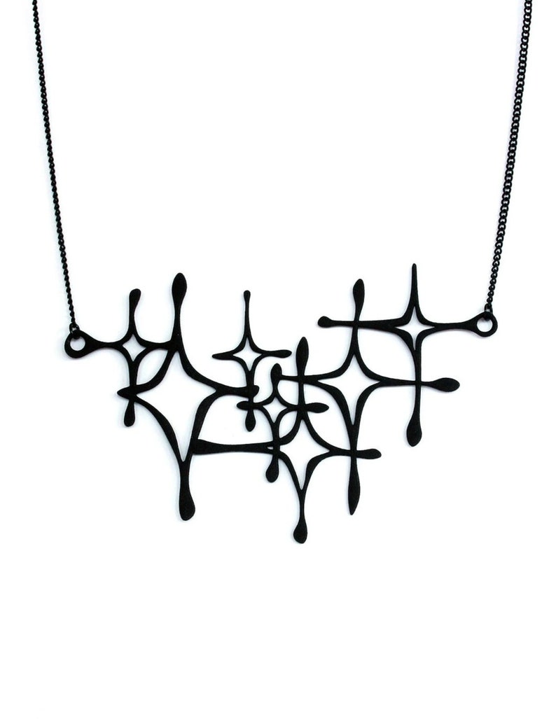 Matte black mid-century modern atomic sparkle necklace displayed on a white background. Witchy 3d printed jewelry by Salem, MA artist Hypnovamp.