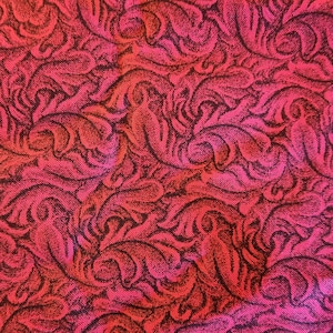 May include: Close-up of a fabric with a repeating pattern of stylized, swirling leaves and vines. The design is in shades of red and pink, with darker red outlines. The fabric has a textured appearance.