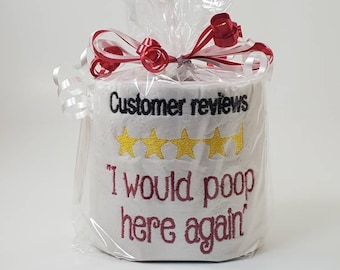 May include: A roll of white toilet paper wrapped in clear plastic with red and white curling ribbons. The paper features black embroidered text reading Customer reviews, four yellow embroidered stars, and red text reading I would poop here again.