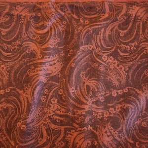 May include: Close-up of fabric with a swirling pattern in shades of brown and orange. The fabric has a floral design and the text "by COUNTRY ESSENTIALS for Connecting Threads" is visible.