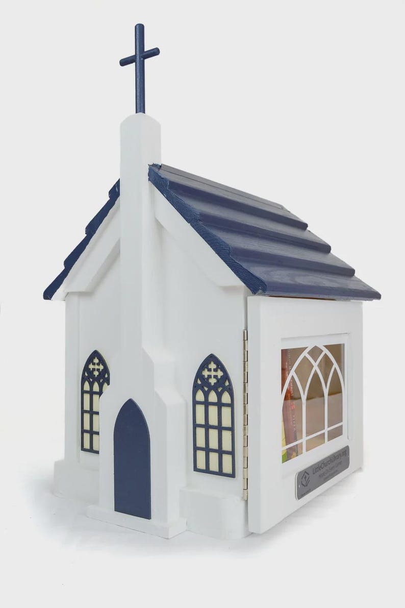 May include: A white wooden church-shaped box with a navy blue roof and cross. The box has arched windows and a door. The box is designed to hold books. The text "LittleChurchCorner" is visible on the side.