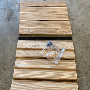 May include: A set of wooden planks for a DIY project, with a bag of nails in the center.